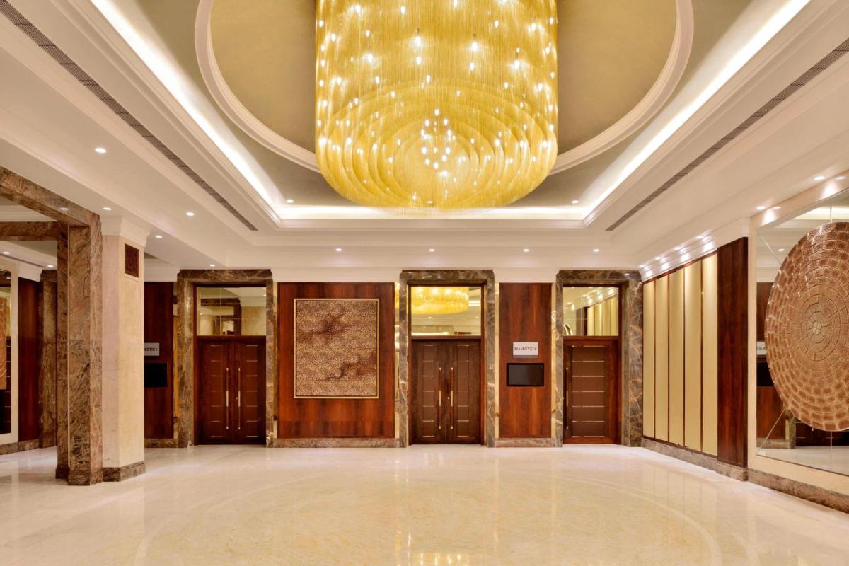a large chandelier hangs from the ceiling of a lobby at Sheraton Grand Pune Bund Garden Hotel in Pune