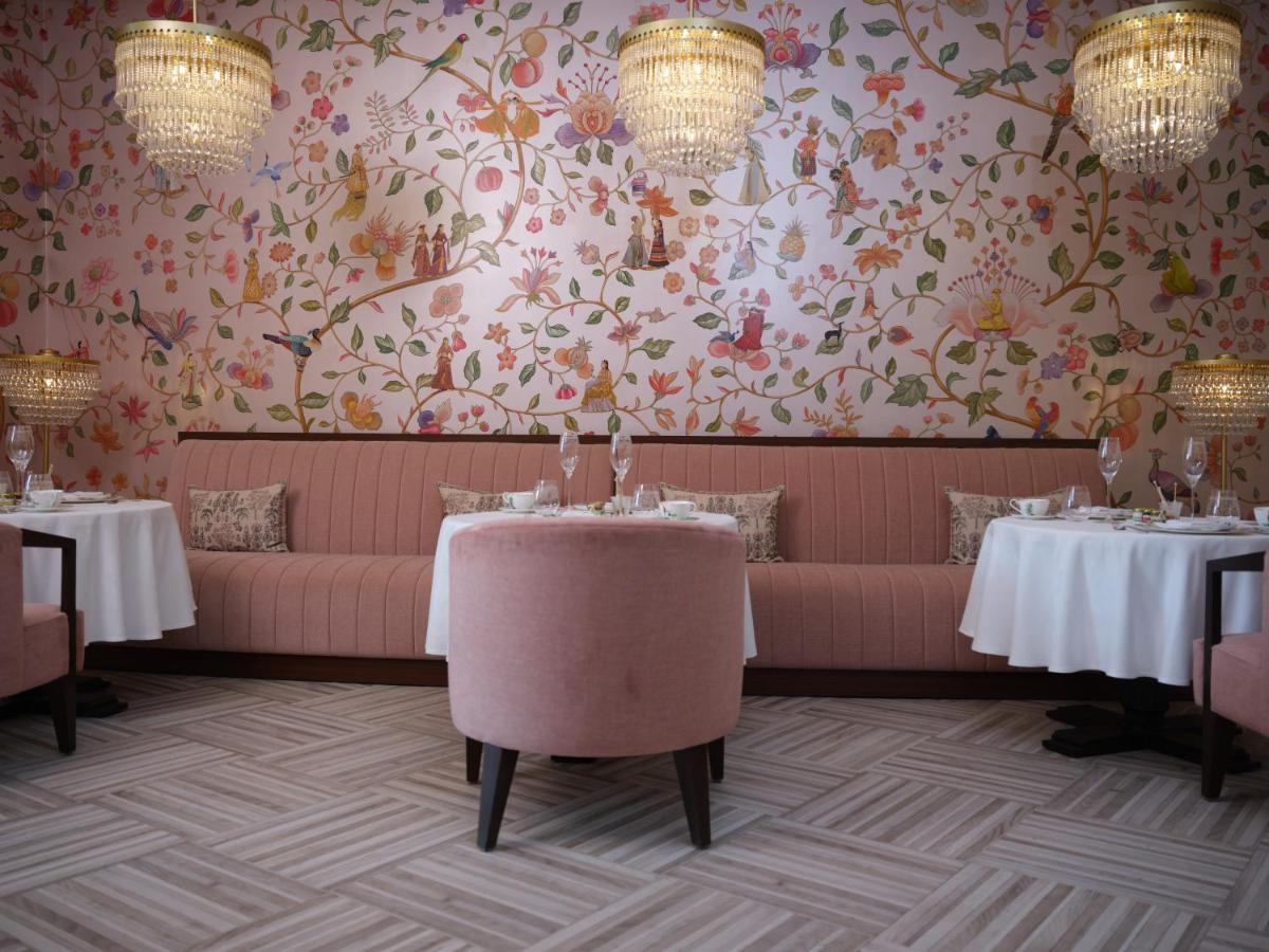 a dining room with tables and a floral wallpaper at The Leela Hyderabad Banjara Hills in Hyderabad