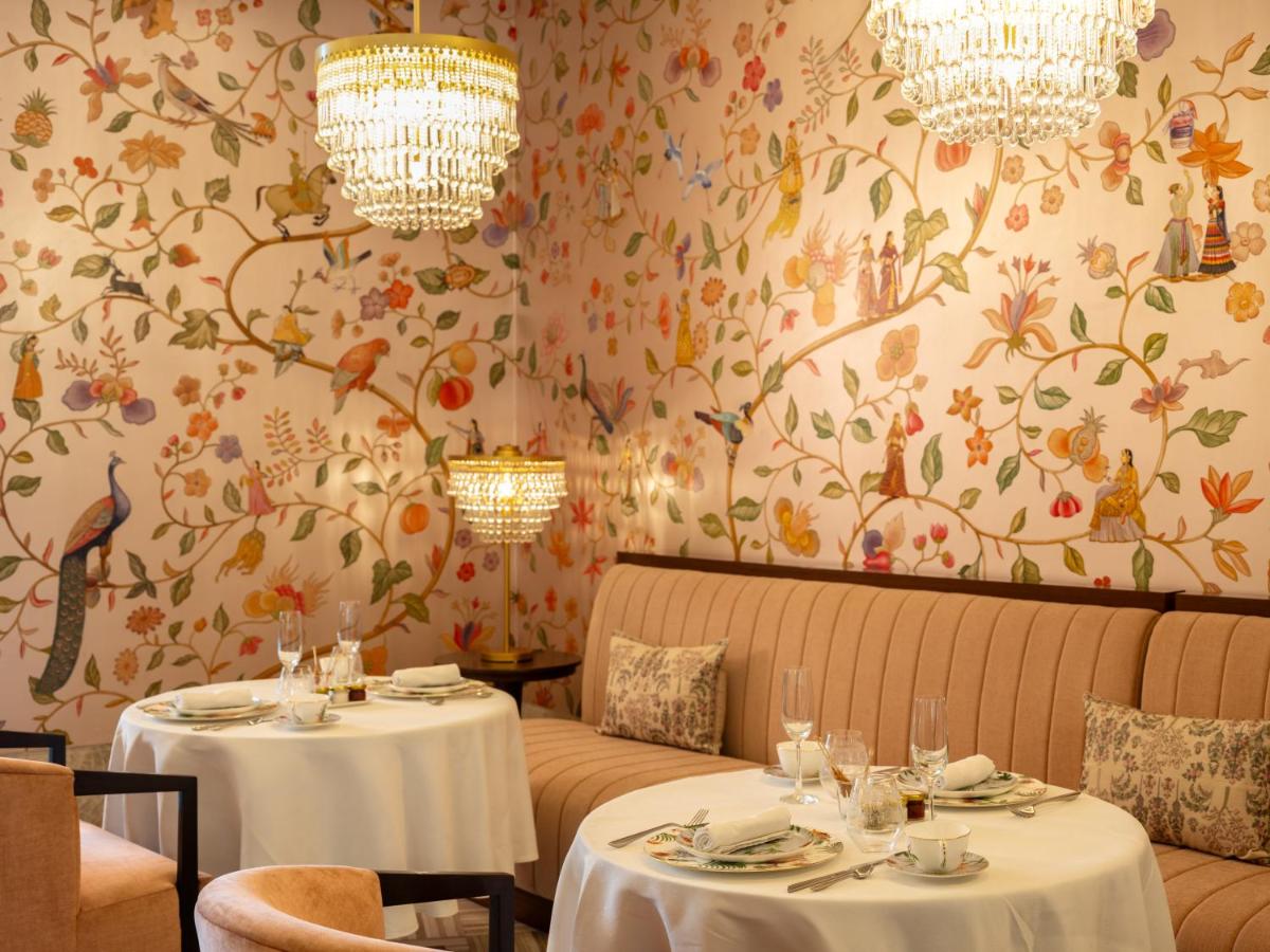 a dining room with two tables and floral wallpaper at The Leela Hyderabad Banjara Hills in Hyderabad