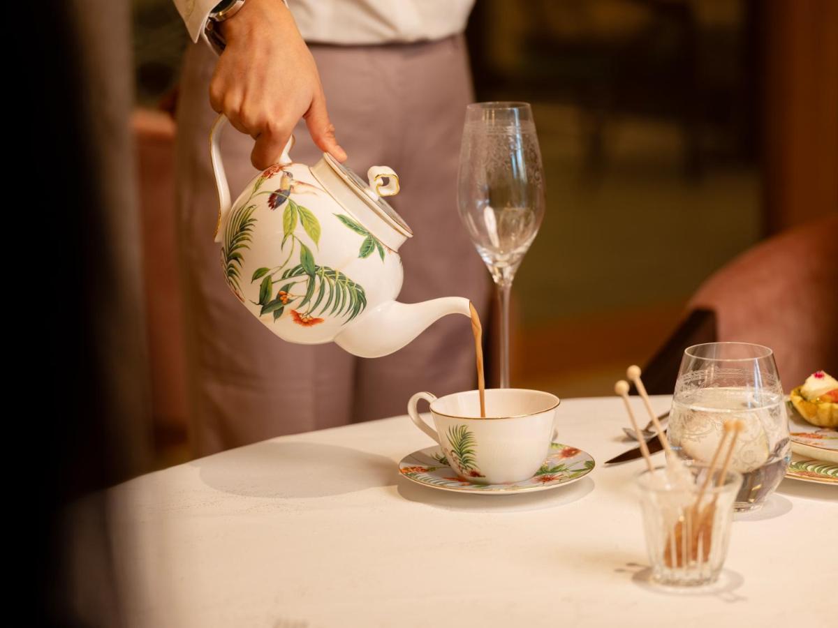 a person pouring coffee into a cup on a table at The Leela Hyderabad Banjara Hills in Hyderabad