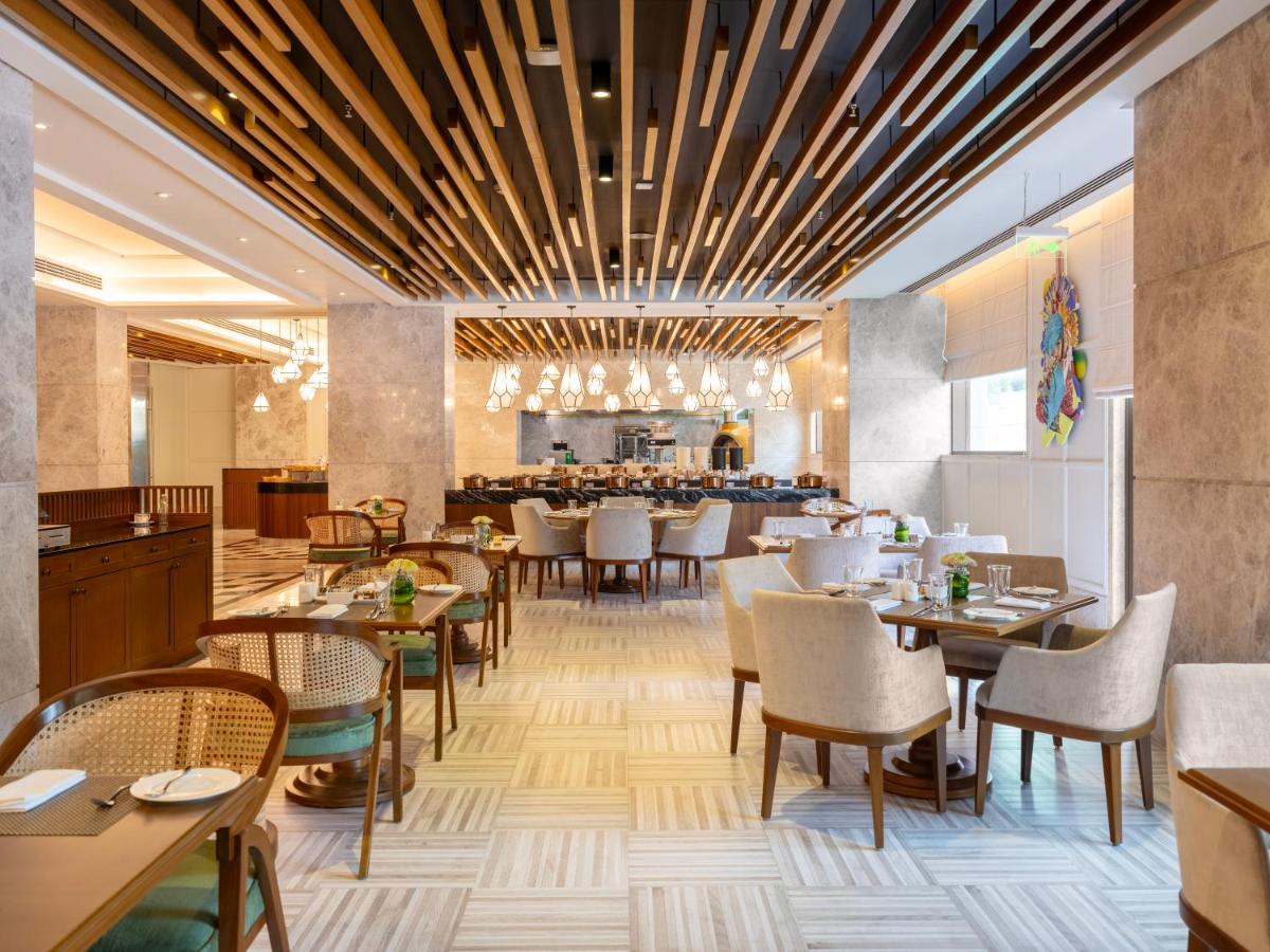 a restaurant with tables and chairs and a bar at The Leela Hyderabad Banjara Hills in Hyderabad