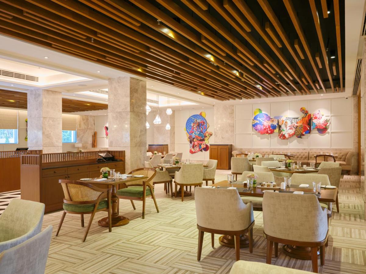 a restaurant with tables and chairs in a room at The Leela Hyderabad Banjara Hills in Hyderabad