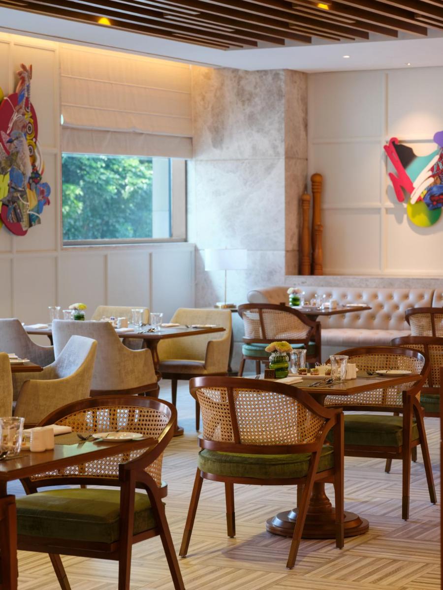 a restaurant with tables and chairs in a room at The Leela Hyderabad Banjara Hills in Hyderabad
