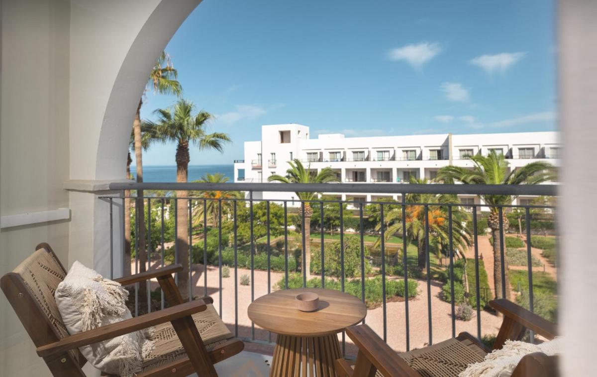 Un balcón con sillas y una mesa y un edificio. en DAIA Slow Beach Hotel Conil - Adults Only Recommended, en Conil de la Frontera