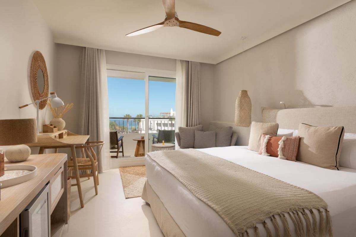 Un dormitorio con una cama y una sala de estar. en DAIA Slow Beach Hotel Conil - Adults Only Recommended, en Conil de la Frontera