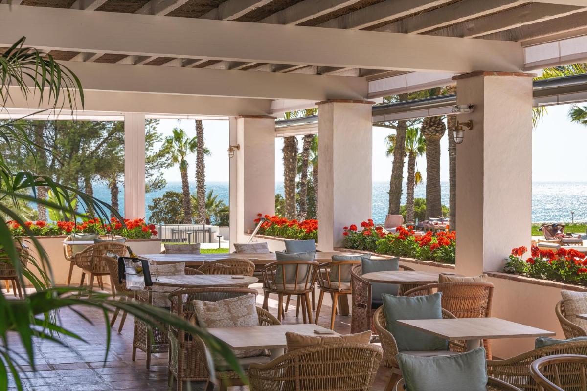 Un restaurante con mesas, sillas y flores. en DAIA Slow Beach Hotel Conil - Adults Only Recommended, en Conil de la Frontera