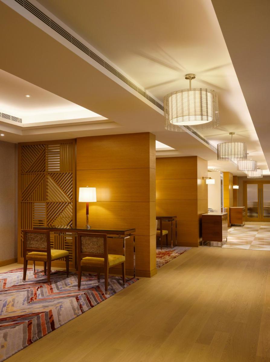 a lobby of a hotel with a desk and chairs at The Leela Hyderabad Banjara Hills in Hyderabad