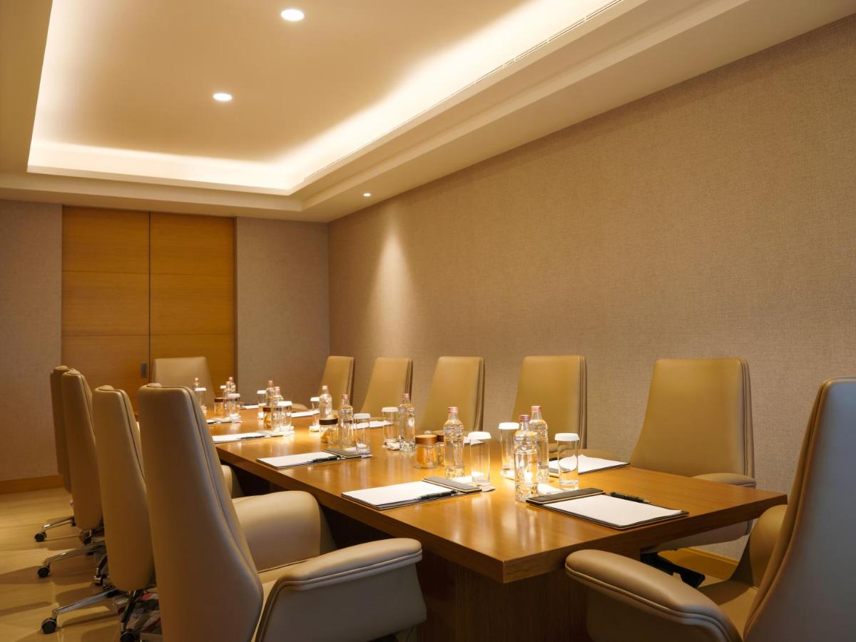 a conference room with a long wooden table and chairs at The Leela Hyderabad Banjara Hills in Hyderabad