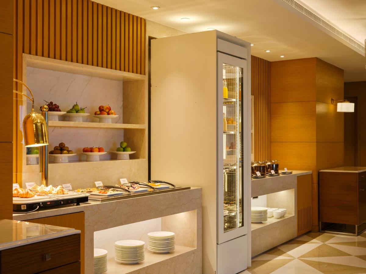 a kitchen with a counter with plates and food at The Leela Hyderabad Banjara Hills in Hyderabad