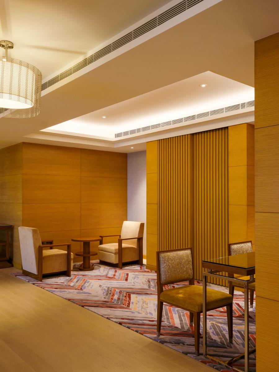 a waiting room with chairs and tables in a building at The Leela Hyderabad Banjara Hills in Hyderabad