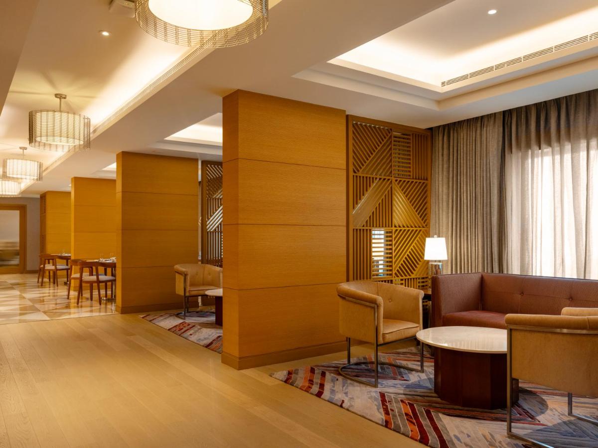 a lobby with a couch and a table and chairs at The Leela Hyderabad Banjara Hills in Hyderabad