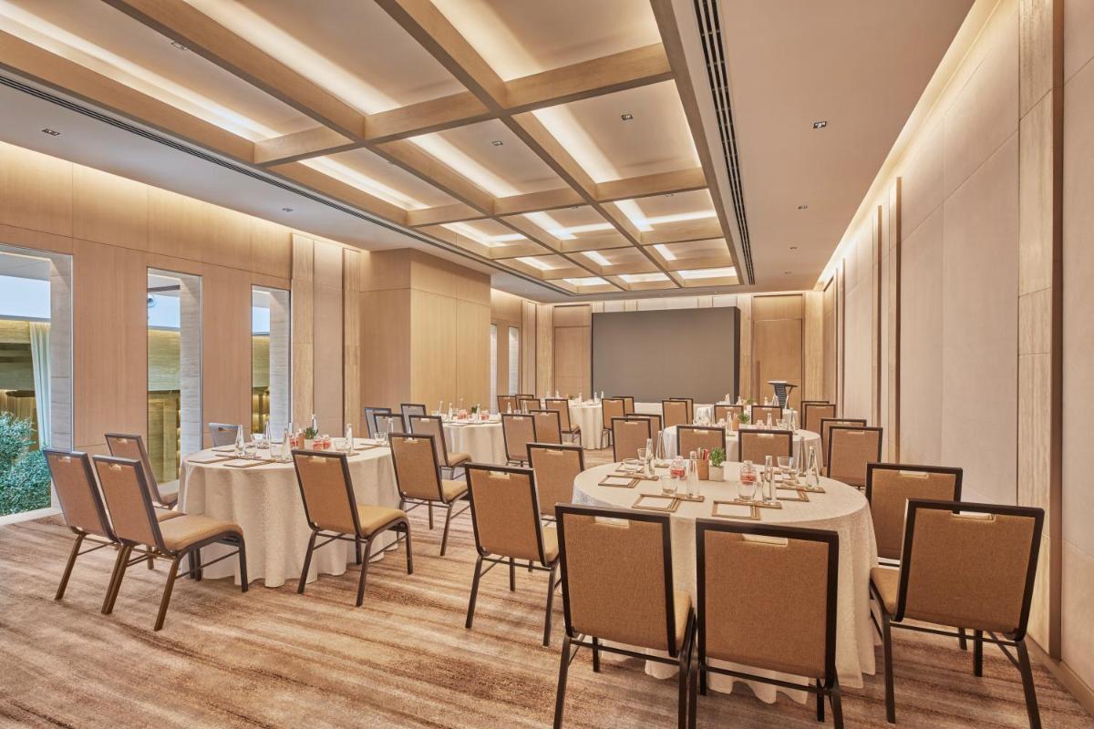 a conference room with tables and chairs and a screen at Hilton Gurugram Baani City Centre in Gurgaon