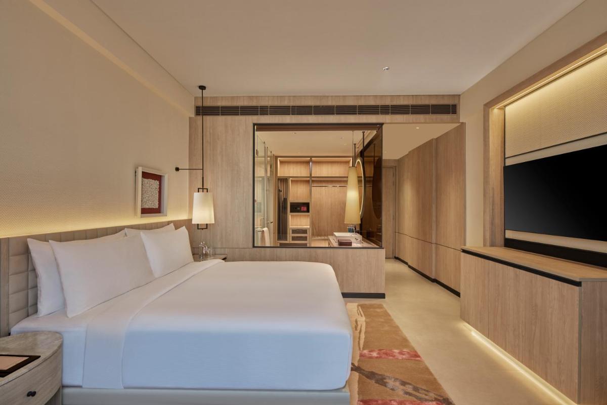 a bedroom with a large white bed and a flat screen tv at Hilton Gurugram Baani City Centre in Gurgaon