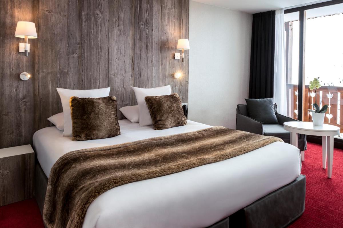 une chambre d'hôtel avec un grand lit et une chaise dans l'établissement Le Pic Blanc, à L'Alpe-d'Huez