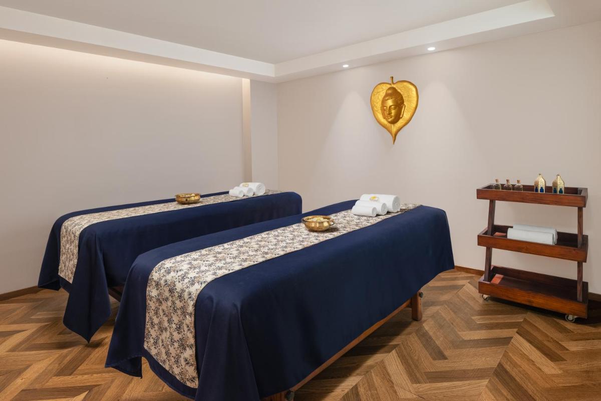 a room with two beds with blue sheets and a table at Courtyard by Marriott Amritsar in Amritsar