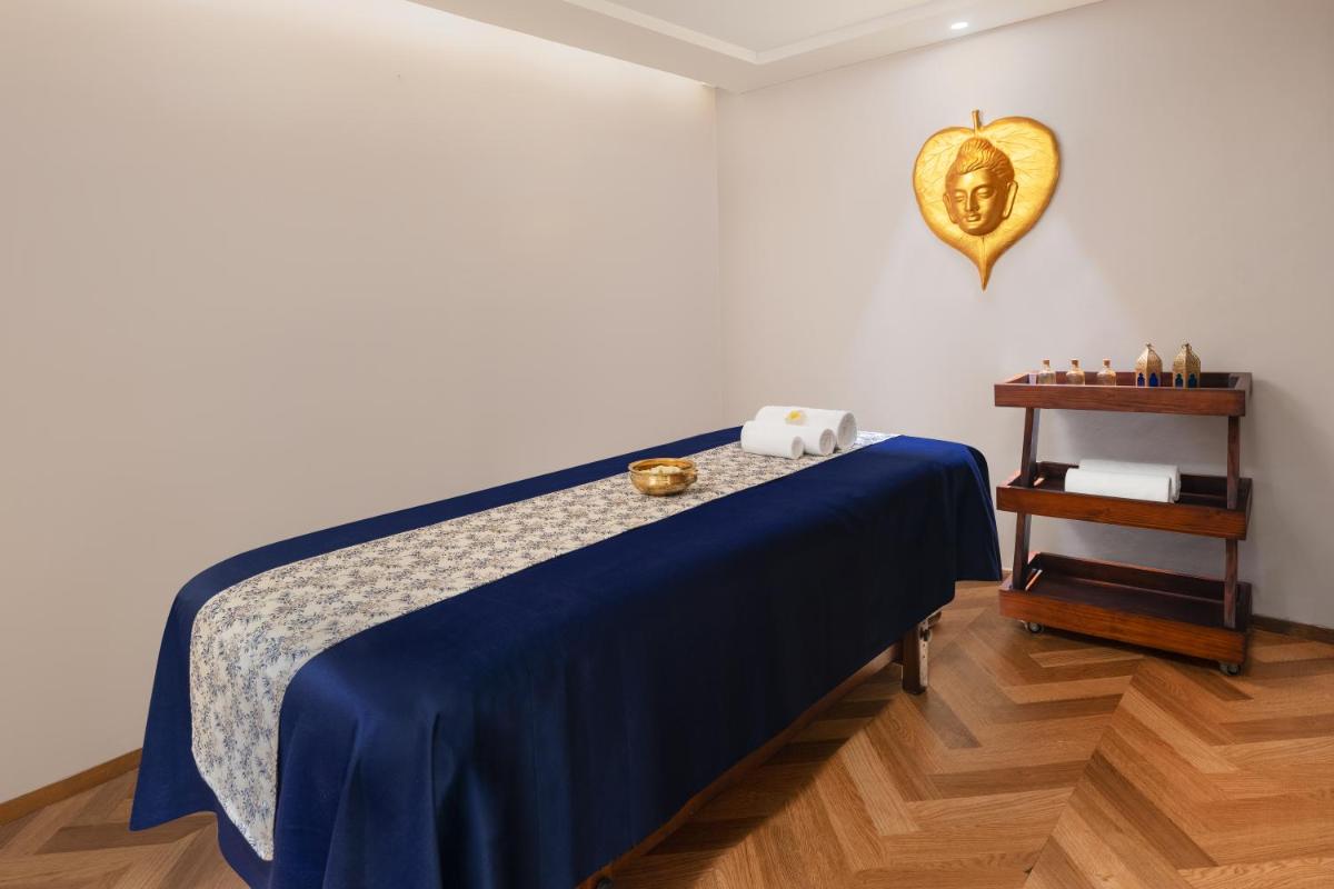 a room with a bed with a blue blanket and a table at Courtyard by Marriott Amritsar in Amritsar