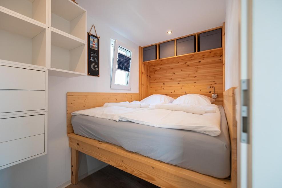 ein Schlafzimmer mit einem großen Bett mit hölzernem Kopfteil in der Unterkunft Schwimmende Häuser im BALTIC SEA RESORT in Kröslin