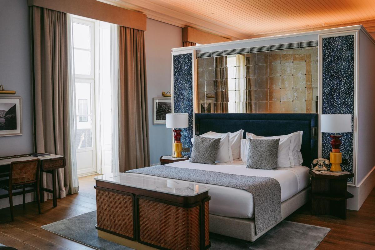 um quarto com uma cama grande e uma janela grande em Palácio Ludovice Wine Experience Hotel em Lisboa