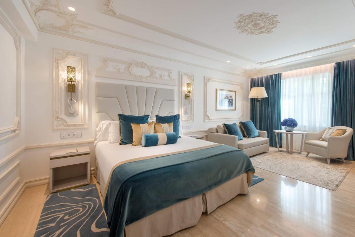 Un dormitorio con una cama grande y una sala de estar. en Gran Hotel Miramar GL, en Málaga 64 fotos más