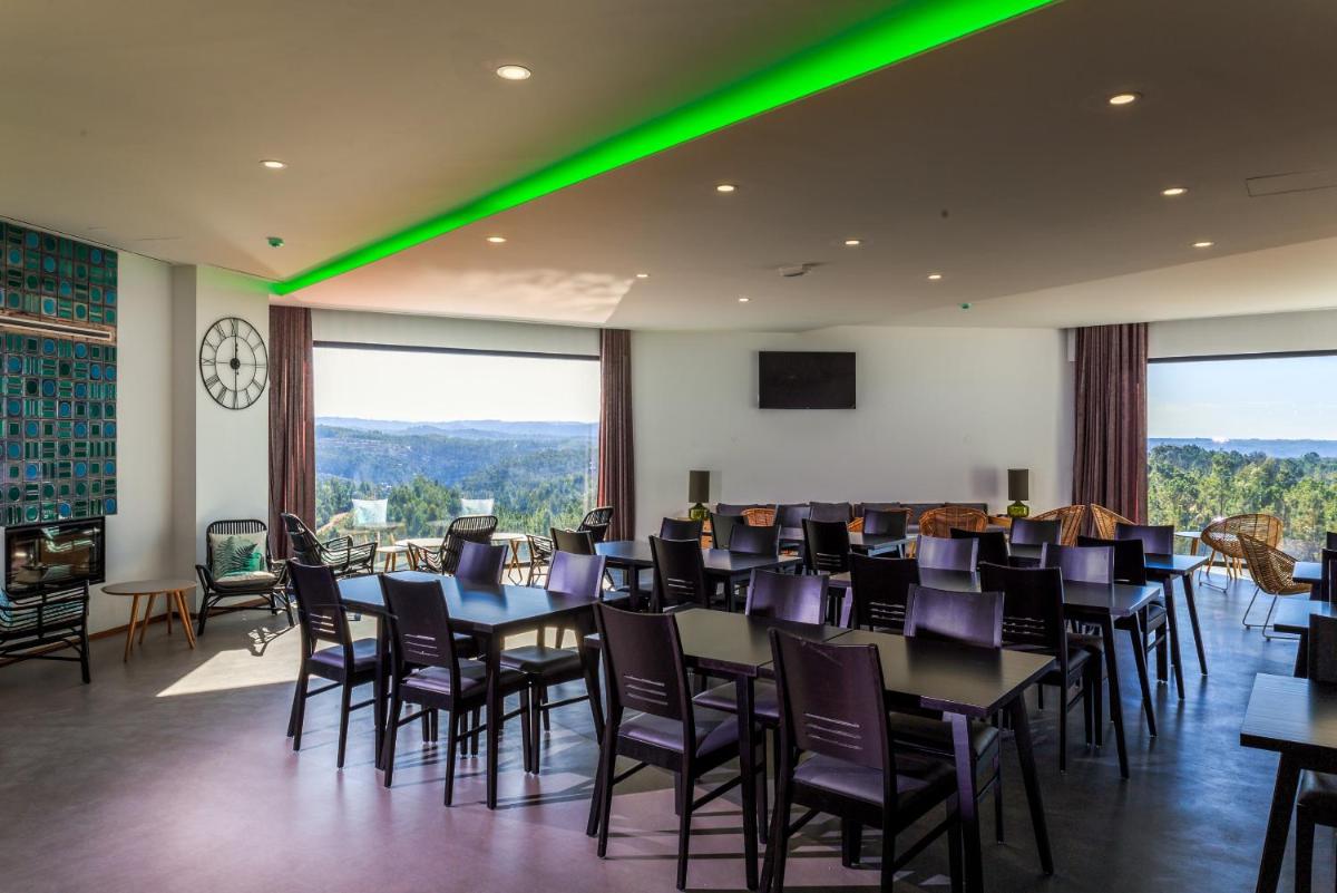 uma sala de jantar com mesas e cadeiras e luzes verdes em Enigma - Nature & Water Hotel em São Teotónio