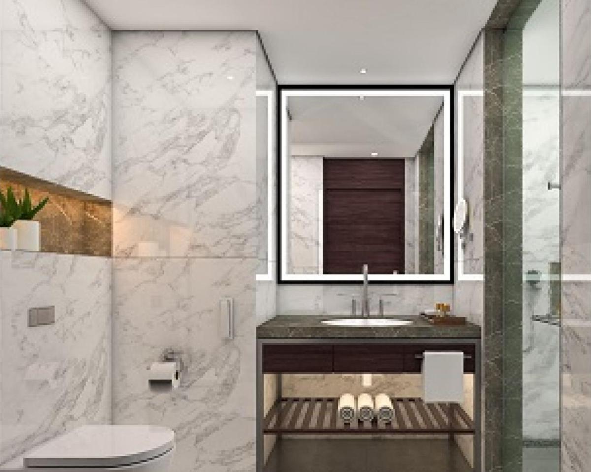 a bathroom with a sink and a toilet and a mirror at Taj Bangalore in Devanahalli-Bangalore