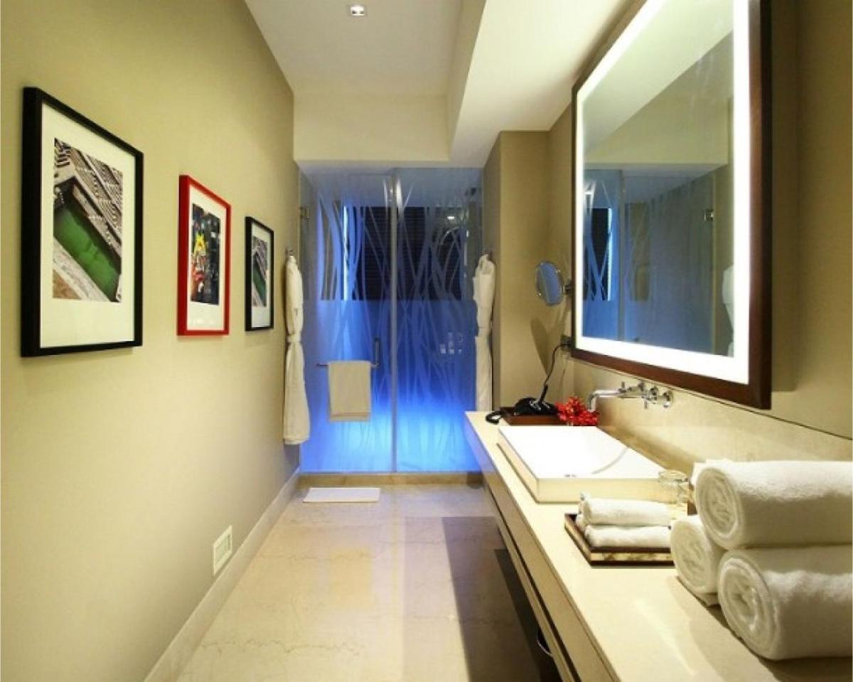 a bathroom with a sink and a large mirror at Taj Bangalore in Devanahalli-Bangalore