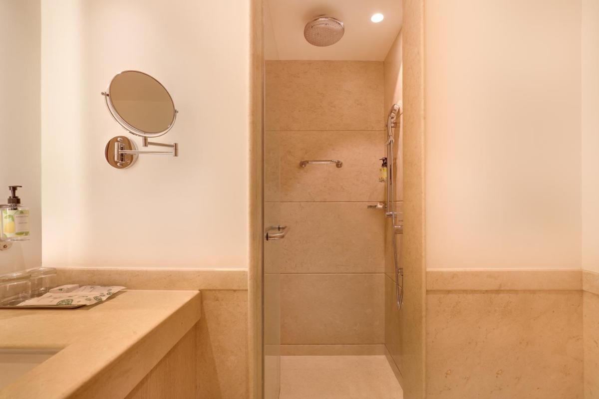 a shower with a glass door in a bathroom at Lemon Tree Premier, Ulsoor Lake, Bengaluru in Bengaluru