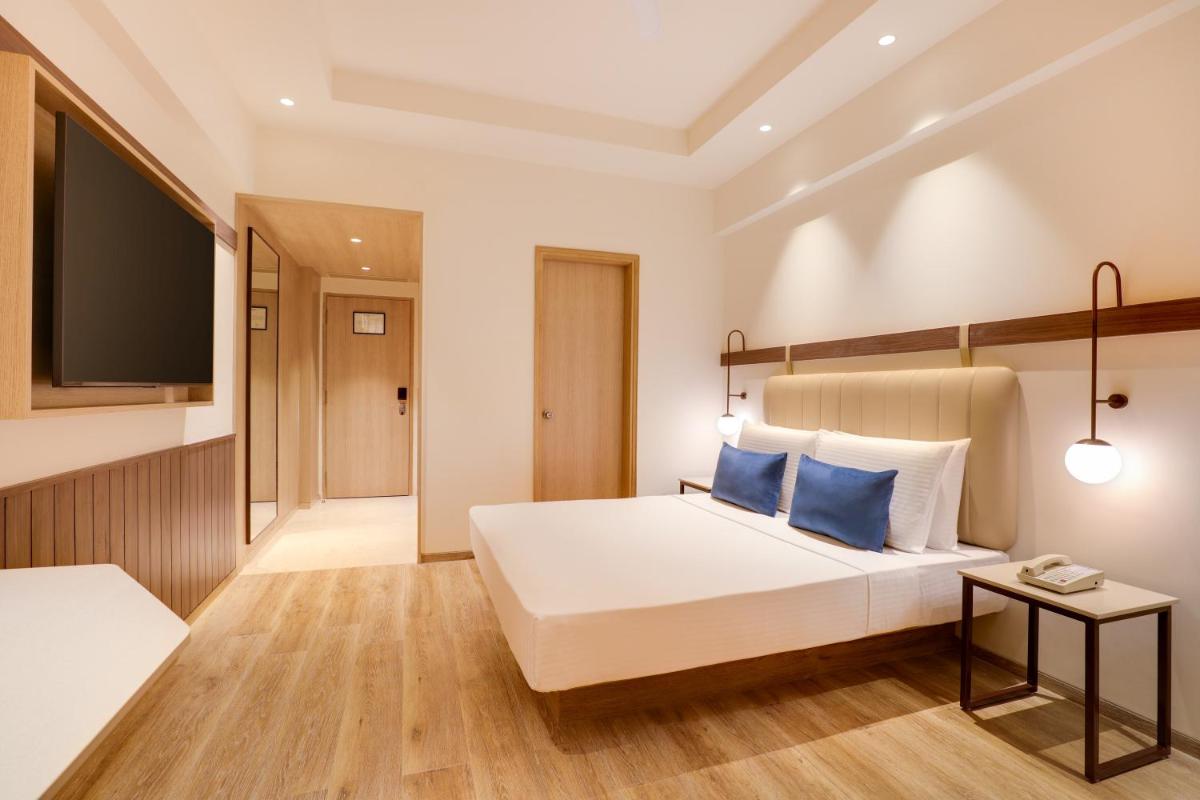 a bedroom with a large white bed with blue pillows at Lemon Tree Premier, Ulsoor Lake, Bengaluru in Bengaluru