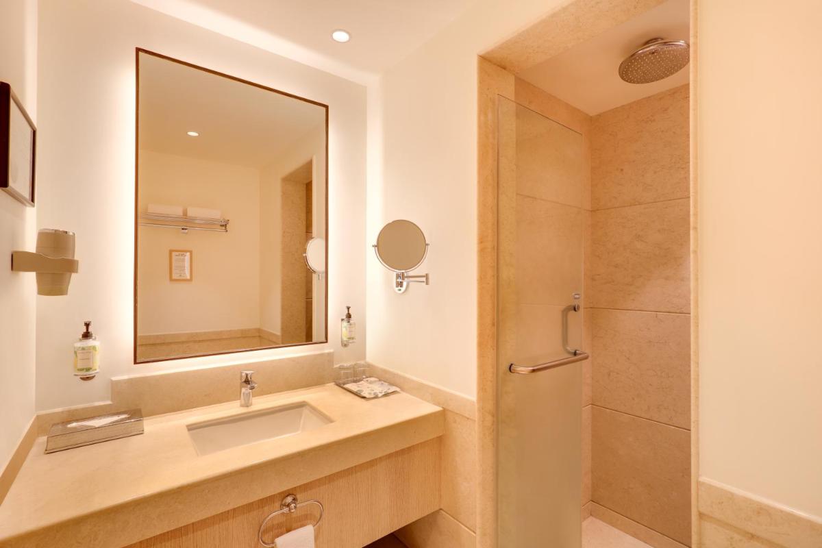 a bathroom with a sink and a mirror and a shower at Lemon Tree Premier, Ulsoor Lake, Bengaluru in Bengaluru