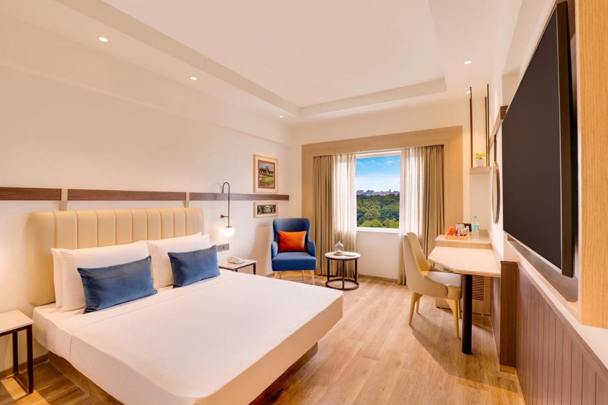 a hotel room with a bed and a desk at Lemon Tree Premier, Ulsoor Lake, Bengaluru in Bengaluru a hotel room with a bed and a desk at Lemon Tree Premier, Ulsoor Lake, Bengaluru in Bengaluru