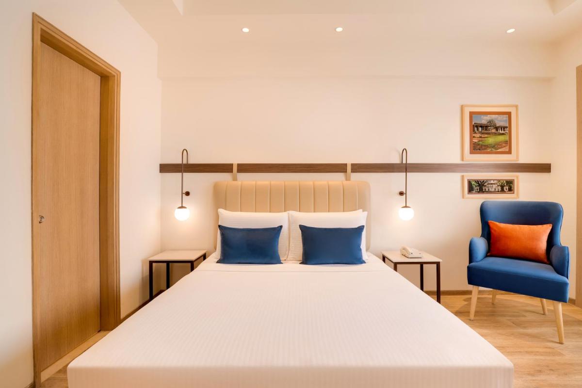 a bedroom with a bed and a blue chair at Lemon Tree Premier, Ulsoor Lake, Bengaluru in Bengaluru