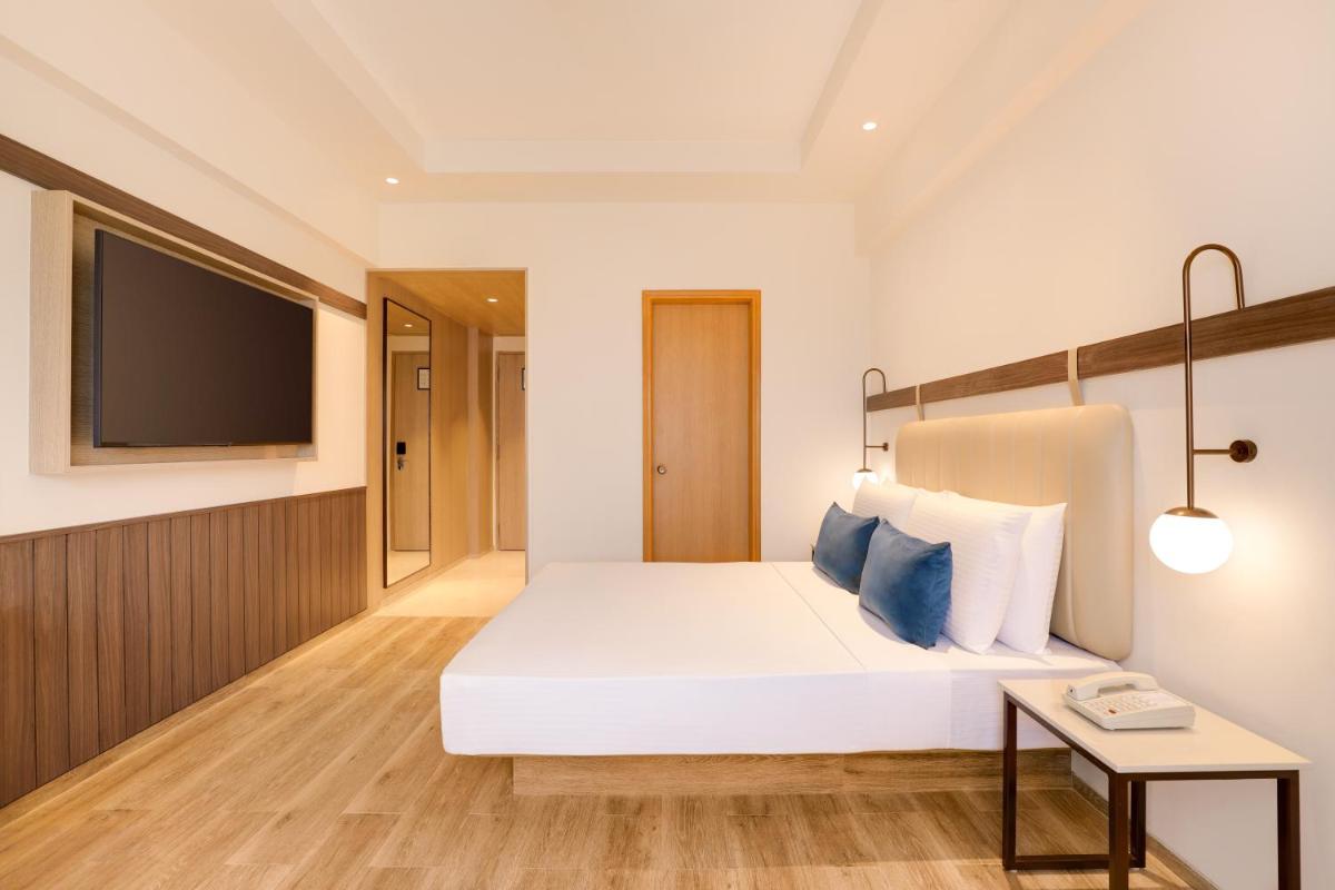 a hotel room with a white bed and a tv at Lemon Tree Premier, Ulsoor Lake, Bengaluru in Bengaluru