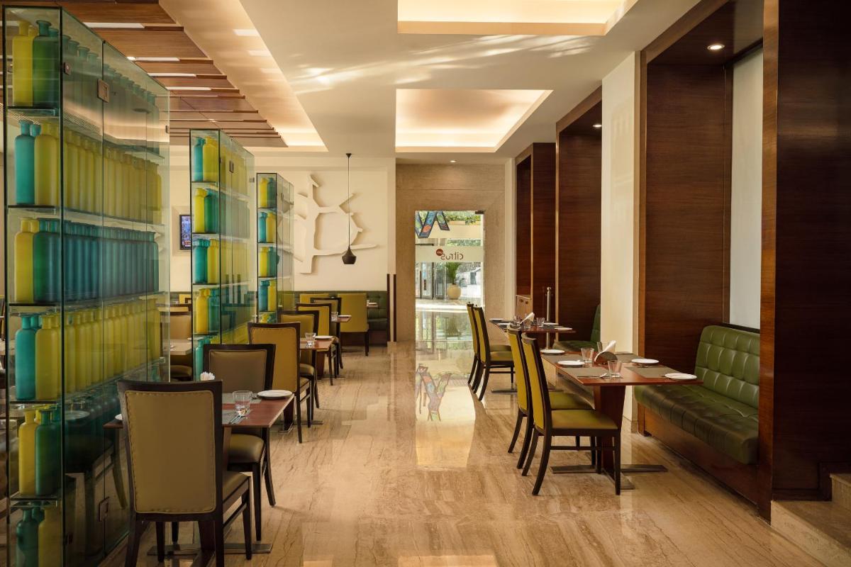 a restaurant with tables and chairs in a room at Lemon Tree Premier, Ulsoor Lake, Bengaluru in Bengaluru a restaurant with tables and chairs in a room at Lemon Tree Premier, Ulsoor Lake, Bengaluru in Bengaluru