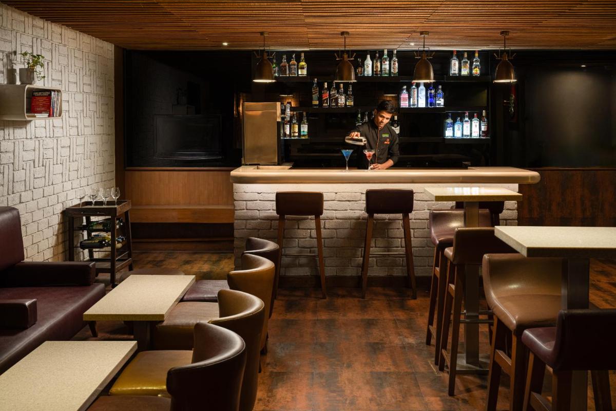a woman standing behind a bar in a restaurant at Lemon Tree Premier, Ulsoor Lake, Bengaluru in Bengaluru