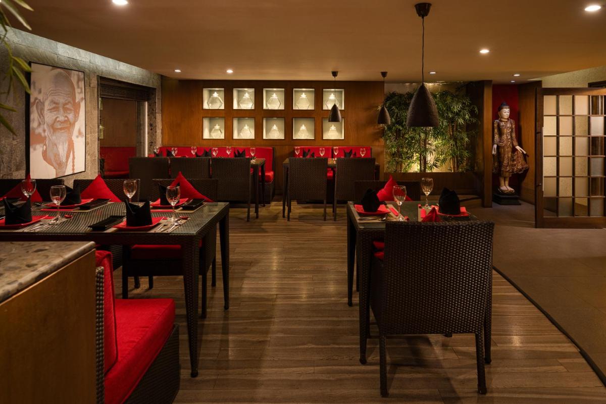 a restaurant with tables and chairs and red seats at Lemon Tree Premier, Ulsoor Lake, Bengaluru in Bengaluru