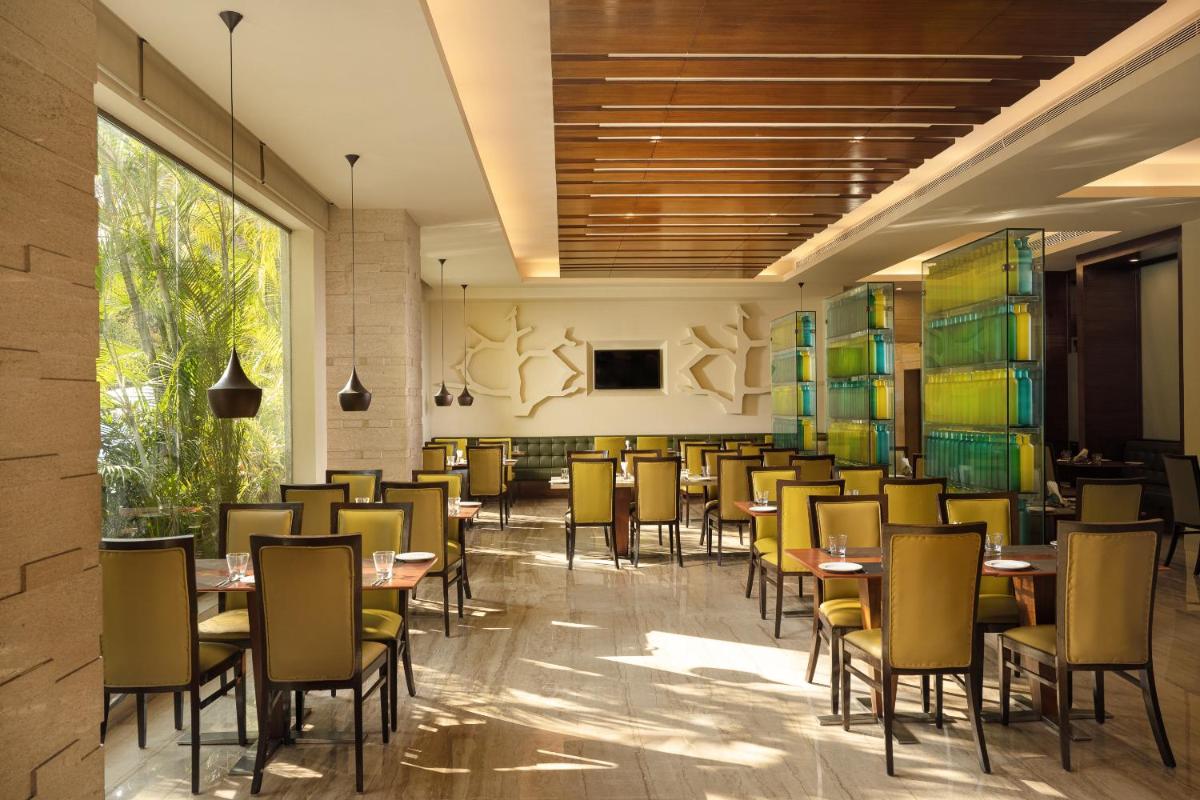 a restaurant with tables and chairs in a room at Lemon Tree Premier, Ulsoor Lake, Bengaluru in Bengaluru