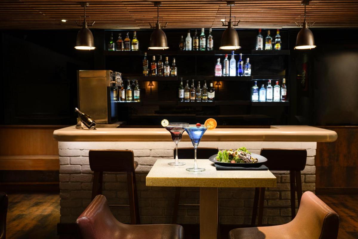 a bar with a table with two glasses and a plate of food at Lemon Tree Premier, Ulsoor Lake, Bengaluru in Bengaluru