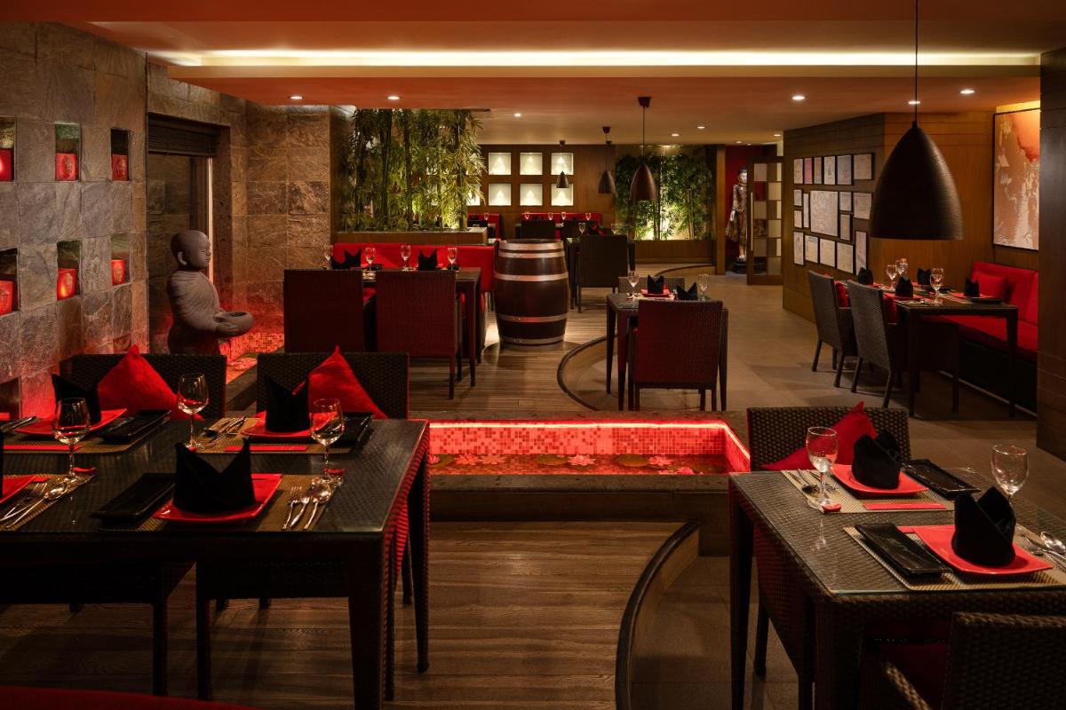 a restaurant with tables and chairs and a bar at Lemon Tree Premier, Ulsoor Lake, Bengaluru in Bengaluru