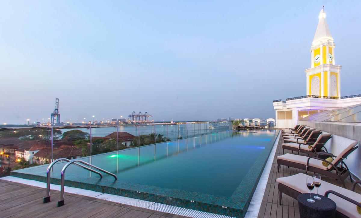 a swimming pool on the roof of a building with a clock tower at Fragrant Nature Kochi - A Five star Classified Hotel in Cochin