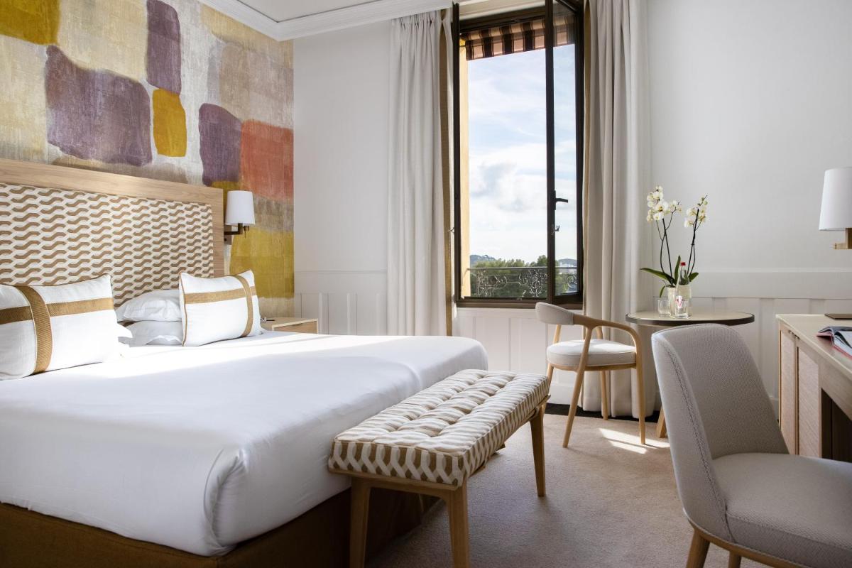 une chambre d'hôtel avec un grand lit et un bureau dans l'établissement Hotel Royal-Riviera, à Saint-Jean-Cap-Ferrat