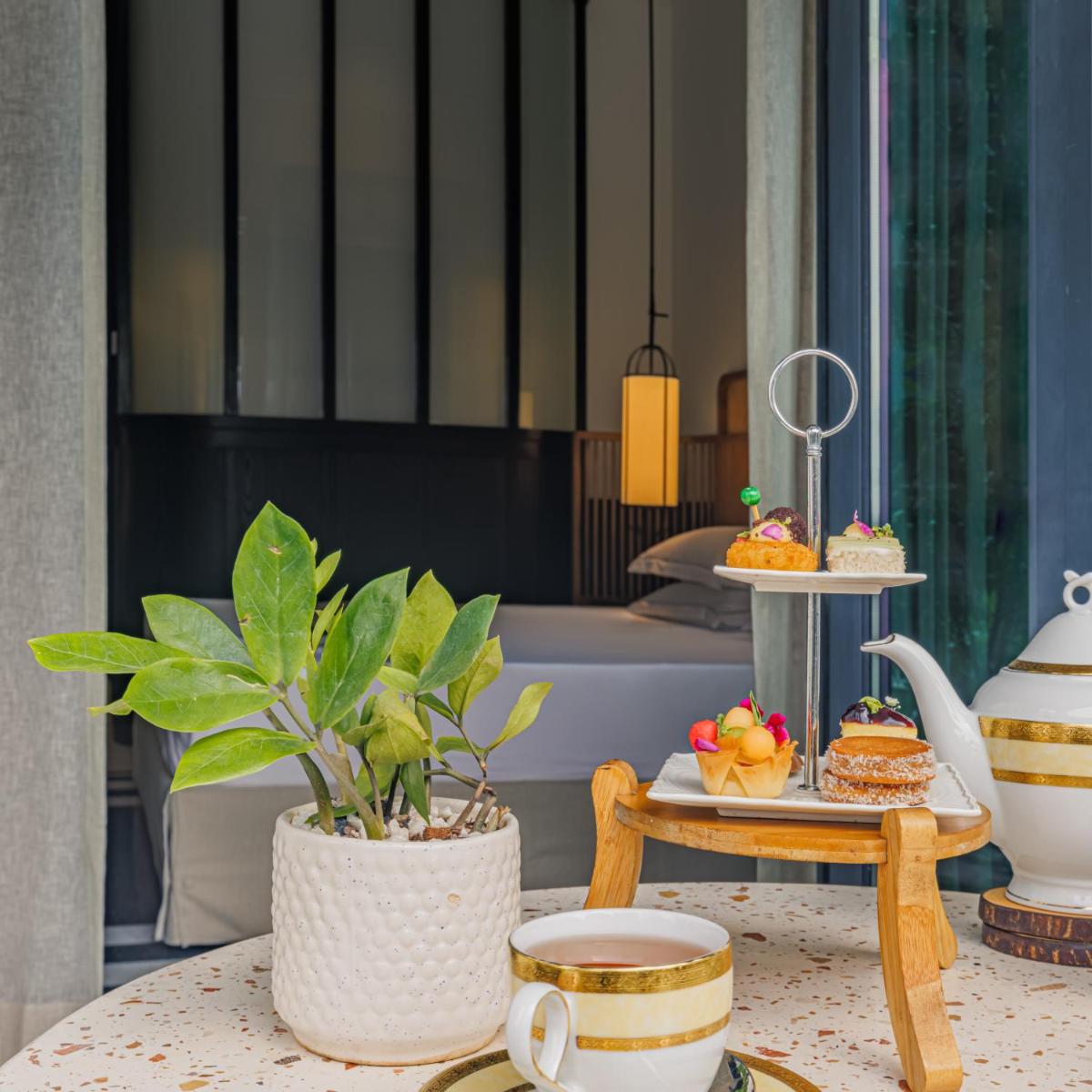 a table with a potted plant and a table with desserts at Taj Taal Kutir in Kolkata
