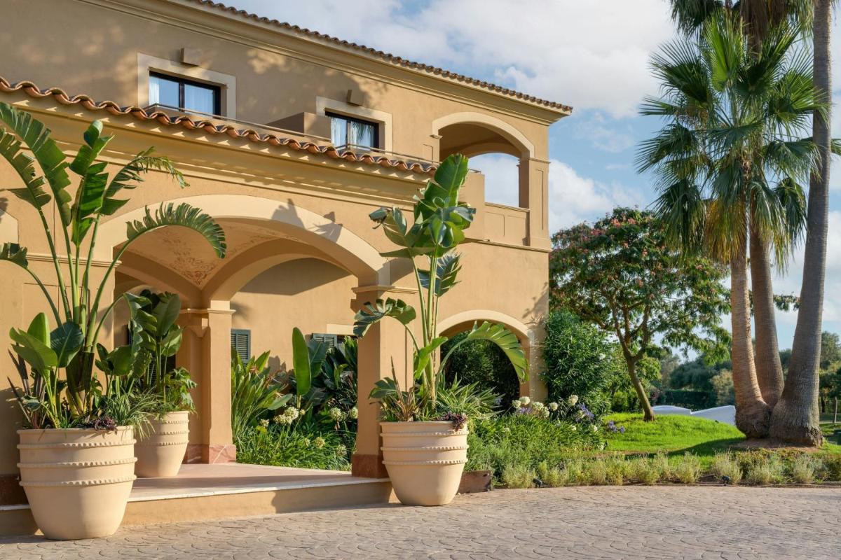 una casa con palmeras y macetas delante de ella en Hacienda Son Antem Golf Resort, Autograph Collection, en Llucmajor