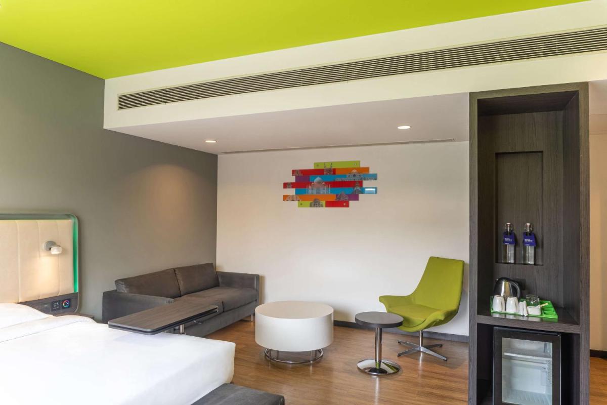 a bedroom with a bed and a couch at Park Inn by Radisson,South Delhi in New Delhi a bedroom with a bed and a couch at Park Inn by Radisson,South Delhi in New Delhi