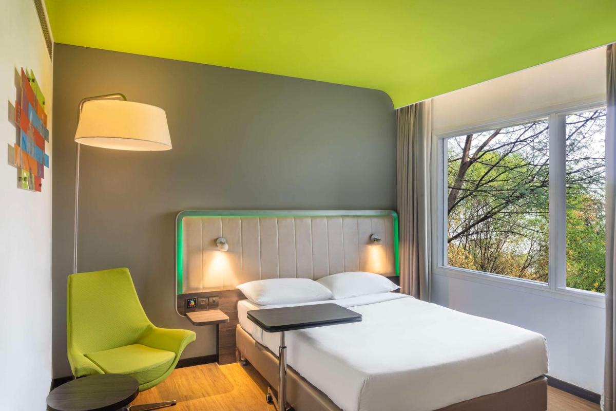 a bedroom with a bed and a chair and a window at Park Inn by Radisson,South Delhi in New Delhi a bedroom with a bed and a chair and a window at Park Inn by Radisson,South Delhi in New Delhi