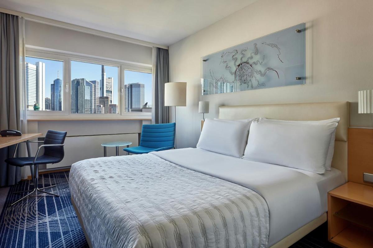 ein Hotelzimmer mit einem Bett, einem Schreibtisch und Stühlen in der Unterkunft Le Méridien Frankfurt in Frankfurt am Main + 37 Fotos ein Hotelzimmer mit einem Bett, einem Schreibtisch und Stühlen in der Unterkunft Le Méridien Frankfurt in Frankfurt am Main + 37 Fotos