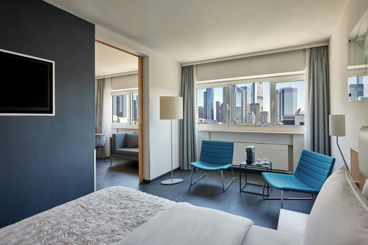 ein Hotelzimmer mit einem Bett und zwei blauen Stühlen in der Unterkunft Le Méridien Frankfurt in Frankfurt am Main ein Hotelzimmer mit einem Bett und zwei blauen Stühlen in der Unterkunft Le Méridien Frankfurt in Frankfurt am Main
