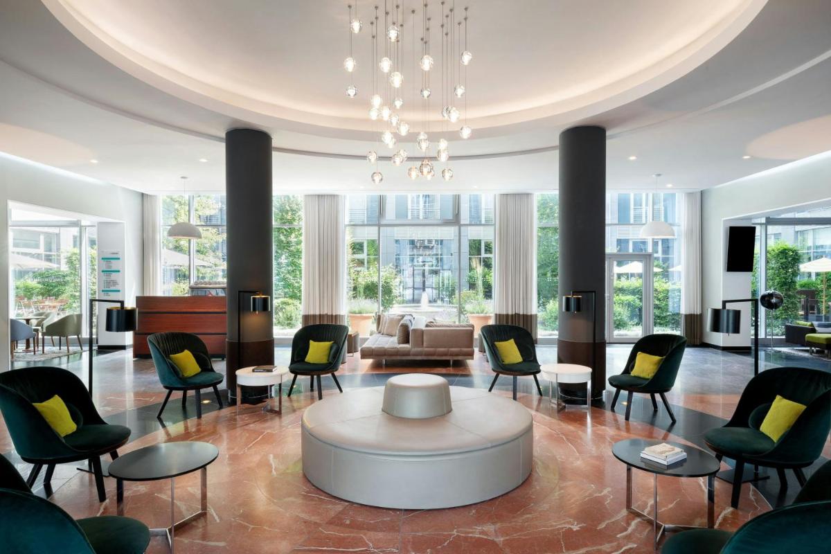 eine Lobby mit Stühlen, einem Tisch und einem Sofa in der Unterkunft Le Méridien Munich in München eine Lobby mit Stühlen, einem Tisch und einem Sofa in der Unterkunft Le Méridien Munich in München