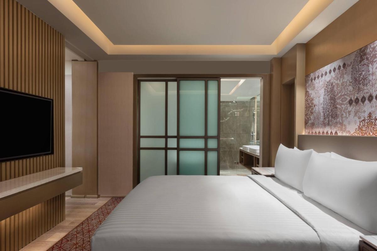a bedroom with a large bed and a tv at Courtyard by Marriott Amritsar in Amritsar