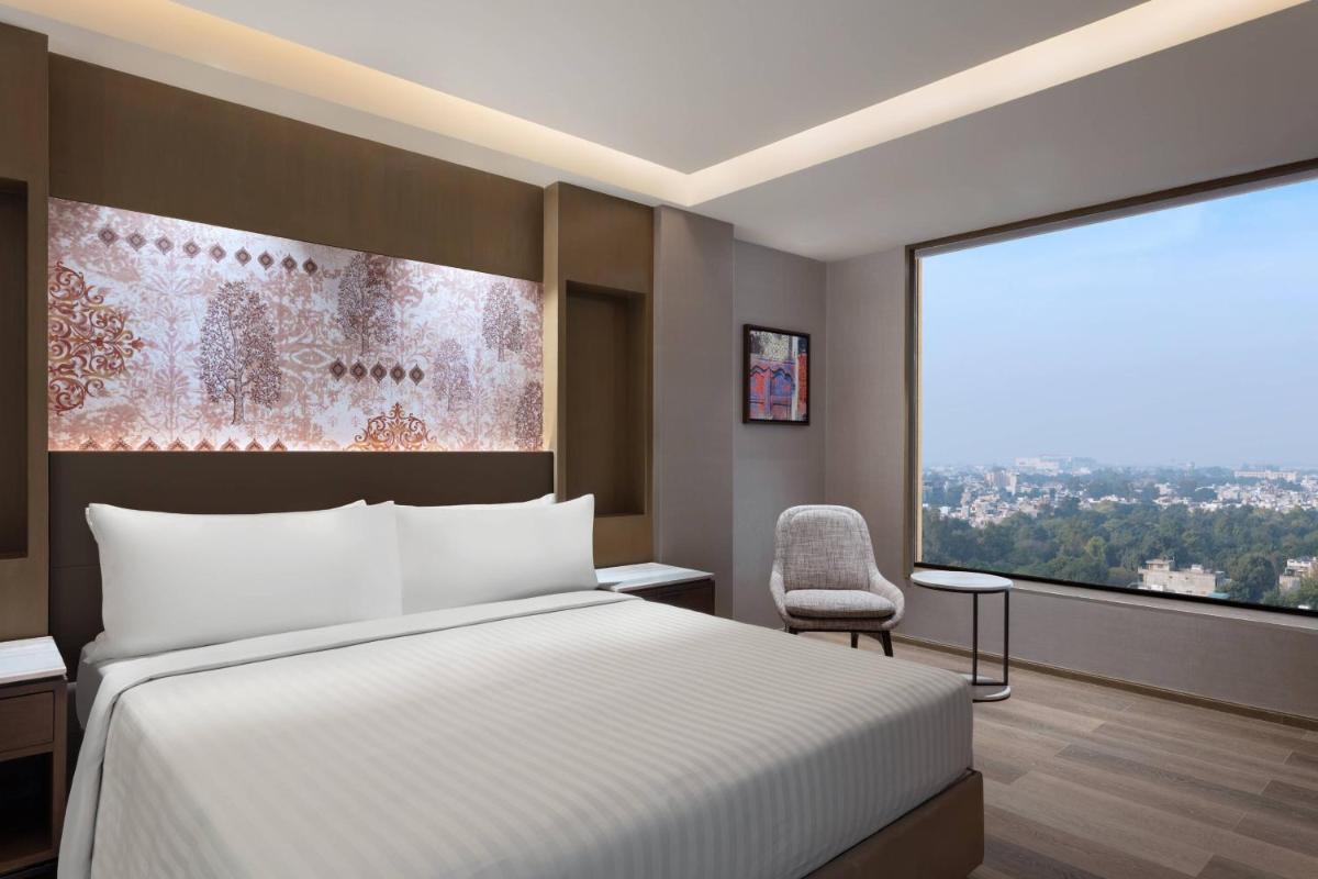 a bedroom with a bed and a large window at Courtyard by Marriott Amritsar in Amritsar