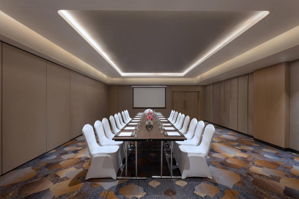 a conference room with a long table and white chairs at Courtyard by Marriott Amritsar in Amritsar